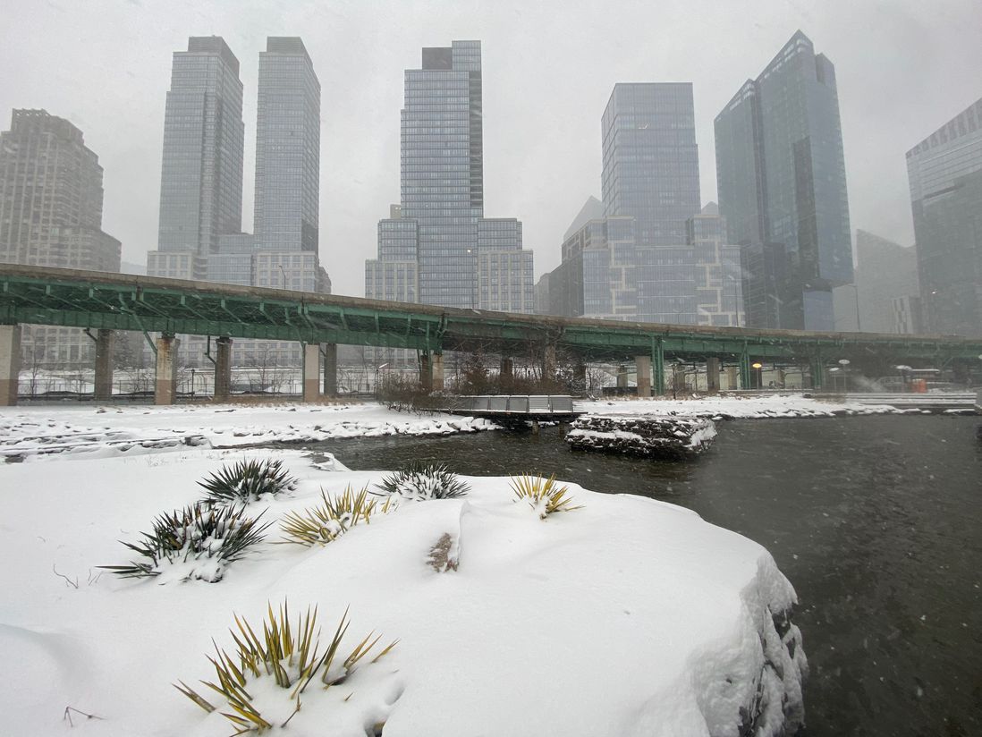 The snowy rock outcropping with a cove and skyscrapers and the West Side Highway in the background